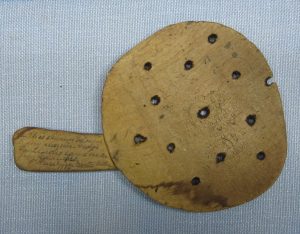 Wooden scoop with holes, handwritten message on handle.