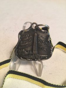 Small metal medallion with image of Standish Monument, on yellow and black ribbon