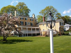 Large yellow house with spring flowers and lamp post. 